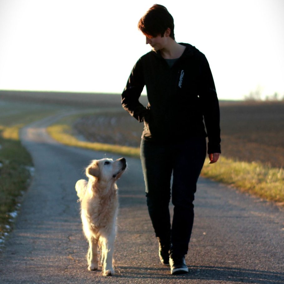Vertrauenshunde - die Hundetrainerin Tatjana und ihr Hund gehen gemeinsam auf einem Weg spazieren 